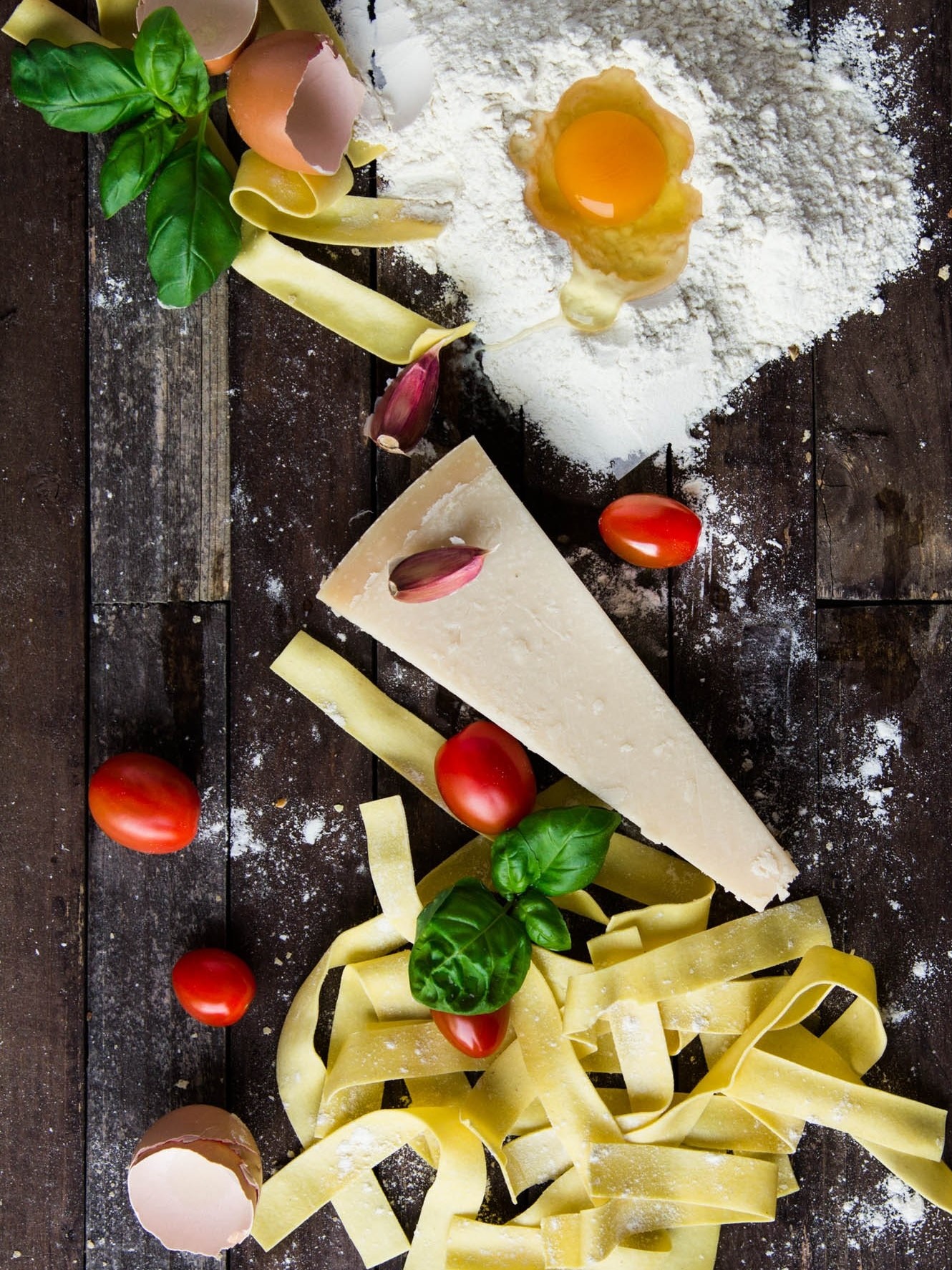 Pasta mit Käse, Tomaten. Basilikum und Ei auf einem dunklen Holztisch